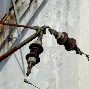 Detailed view of an old, rusty current collector or insulator attached to a wall