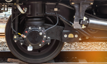 Close-up of a rail vehicle's wheel assembly with visible suspension and brake components