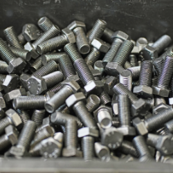 Close-up of stacked hexagonal metal screws in a box, used in rail transport