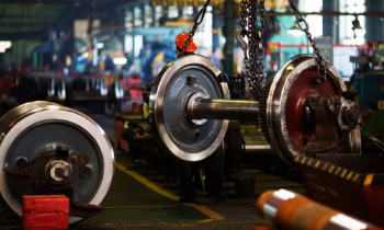 Rail vehicle axle and wheel components being assembled in an industrial workshop