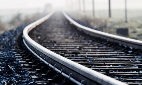 Railway tracks leading into the distance, with gravel and light fog in the background